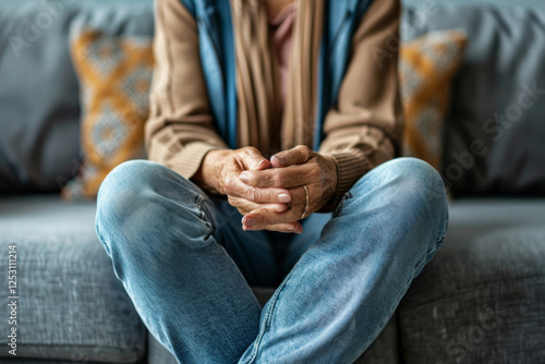 Wallpaper Mural An elderly woman sitting on a couch, hands clasped in a prayer gesture, wearing a cozy knitted sweater. Torontodigital.ca