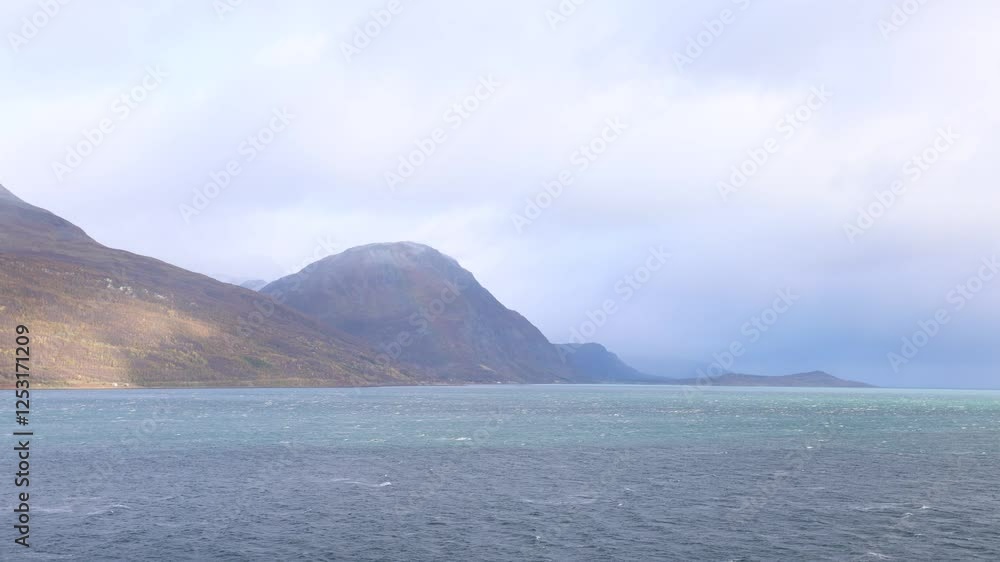 Autumn landscape of the Lyngen Alps in Northern Norway with snowy peaks, dramatic clouds, and a tranquil fjord. Autumn landscape of the Lyngen Alps in Northern Norway with snowy peaks, dramatic clouds, and a tranquil fjord.