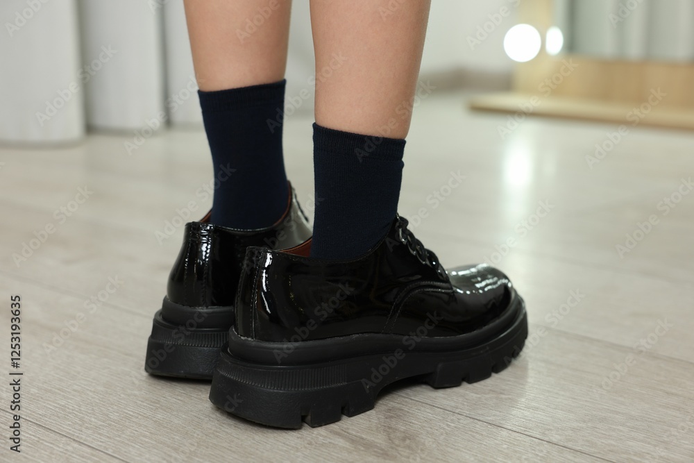 Little girl wearing oversized shoes indoors, closeup Little girl wearing oversized shoes indoors, closeup