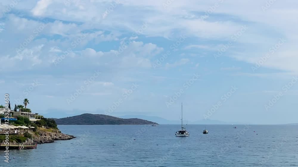 Coastal view with sailboats anchored near a tree-lined shore, picturesque white houses, and distant mountains blending into the calm waters Coastal view with sailboats anchored near a tree-lined shore, picturesque white houses, and distant mountains blending into the calm waters