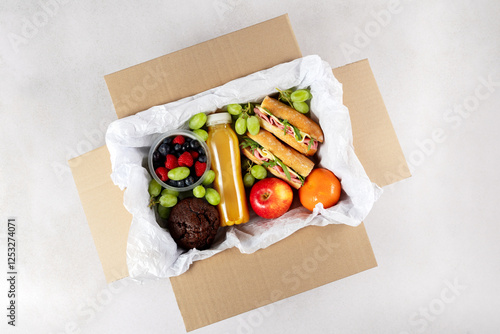 Ready prepared brunch box with sandwiches, fruits, berries and smoothie. Quick lunch break, time saving healthy meal photo