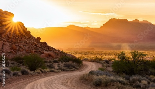 curved dirt road winds through rocky terrain in a desert landscape at golden hour