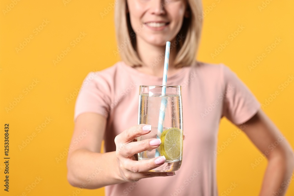 Woman with glass of lemonade on orange background, closeup. Refreshing drink Woman with glass of lemonade on orange background, closeup. Refreshing drink