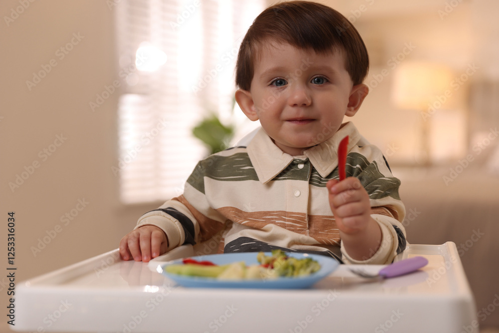 Cute little baby eating healthy food in high chair at home Cute little baby eating healthy food in high chair at home