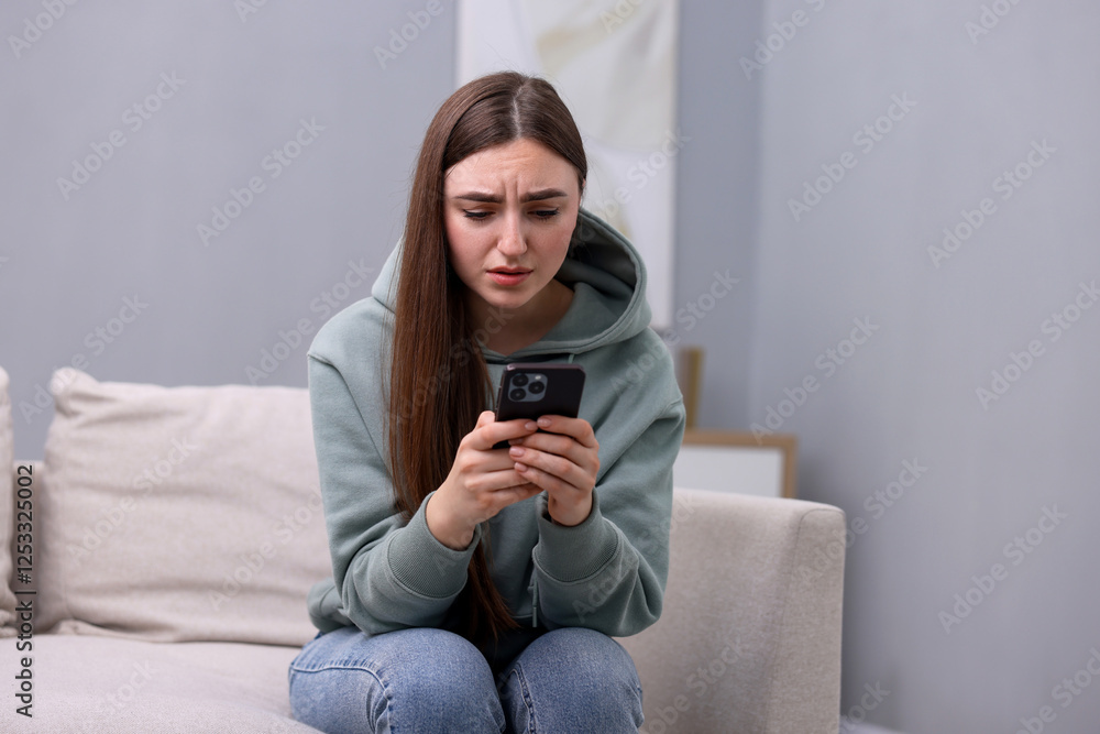 Depressed woman calling hotline for mental health help on sofa at home