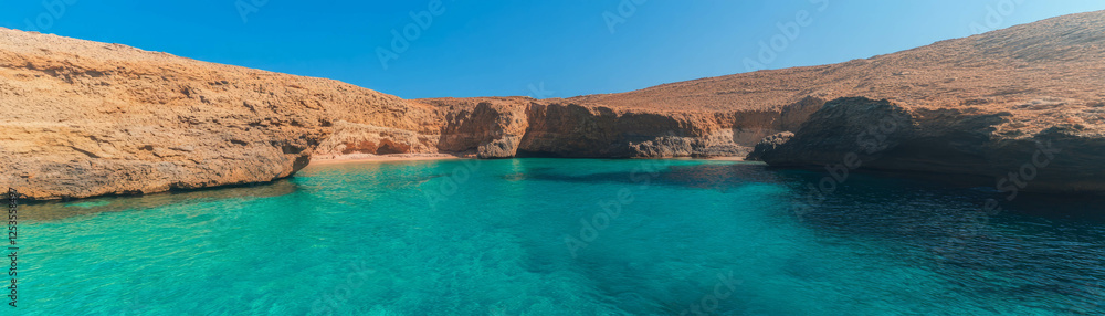Small cove with tranquil turquoise waters and rocky surroundings on a bright day