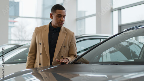 African American man unsure pensive male client customer buyer choose automobile in dealership store ethnic guy millennial think doubt touch car hood dream buying auto expensive purchase in showroom