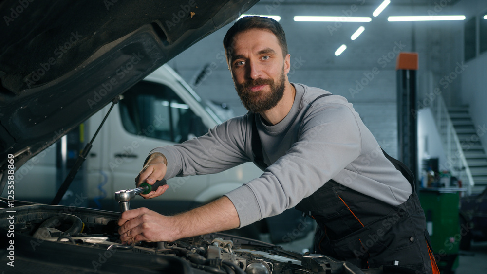 Caucasian man technician worker repairman mechanic check fix problem under open automobile hood smiling happy male guy in uniform use spanner key instrument repair car in garage auto service station Caucasian man technician worker repairman mechanic check fix problem under open automobile hood smiling happy male guy in uniform use spanner key instrument repair car in garage auto service station