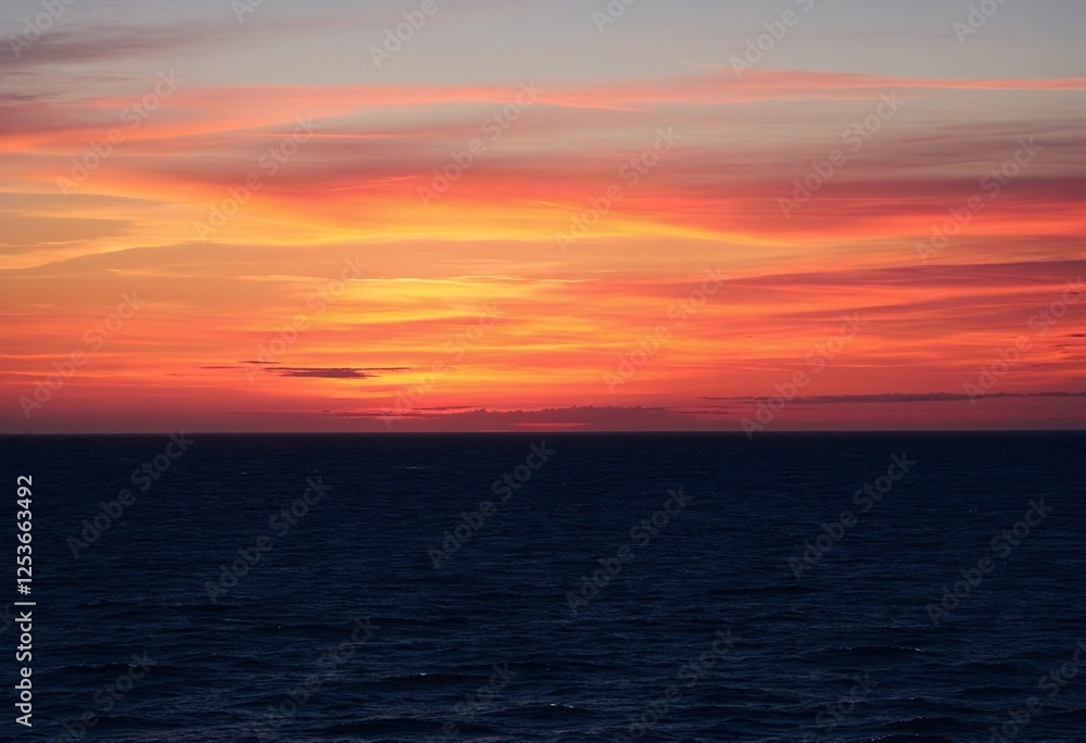Obraz premium Stunning Ocean Sunset Bathed in Fiery Orange and Pink Colors