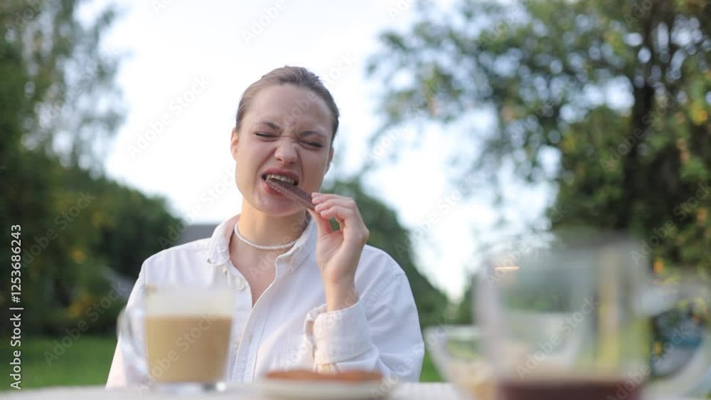woman eating chocolate in the garden in summer woman eating chocolate in the garden in summer