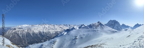 Majestic snow-covered mountains under clear blue sky during winter season in remote alpine region photo