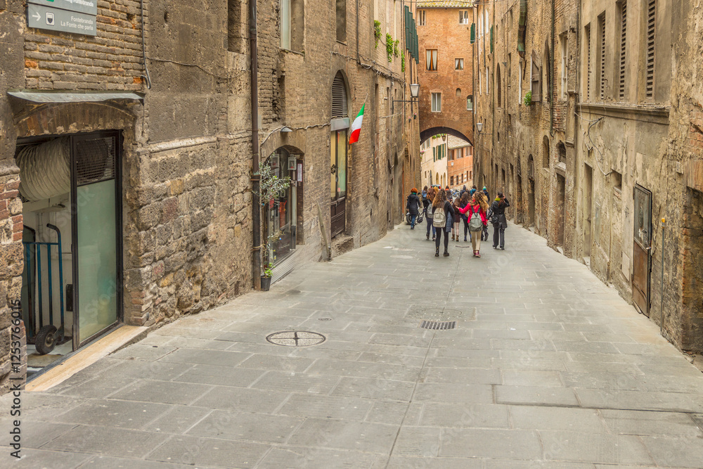 Obraz premium Old street in the historical center of Siena, the UNESCO World Heritage Centre unchanged for 13-14 centuries, with its medieval streets looked like in the early Middle Ages. Italy, 2019