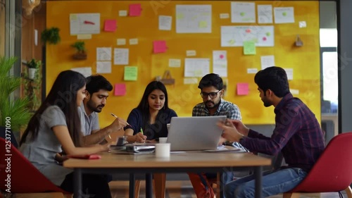 Young Indian entrepreneurs collaborating, sharing startup strategy while working on laptop in contemporary workspace
