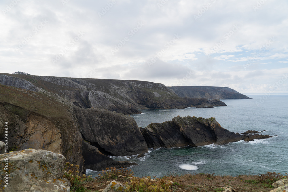 Paysage sauvage sur la presqu’île de Crozon. Sous un ciel bleu parsemé de nuages blancs, les falaises abruptes plongent dans la mer d’Iroise, offrant une vue spectaculaire sur l’océan. Paysage sauvage sur la presqu’île de Crozon. Sous un ciel bleu parsemé de nuages blancs, les falaises abruptes plongent dans la mer d’Iroise, offrant une vue spectaculaire sur l’océan.