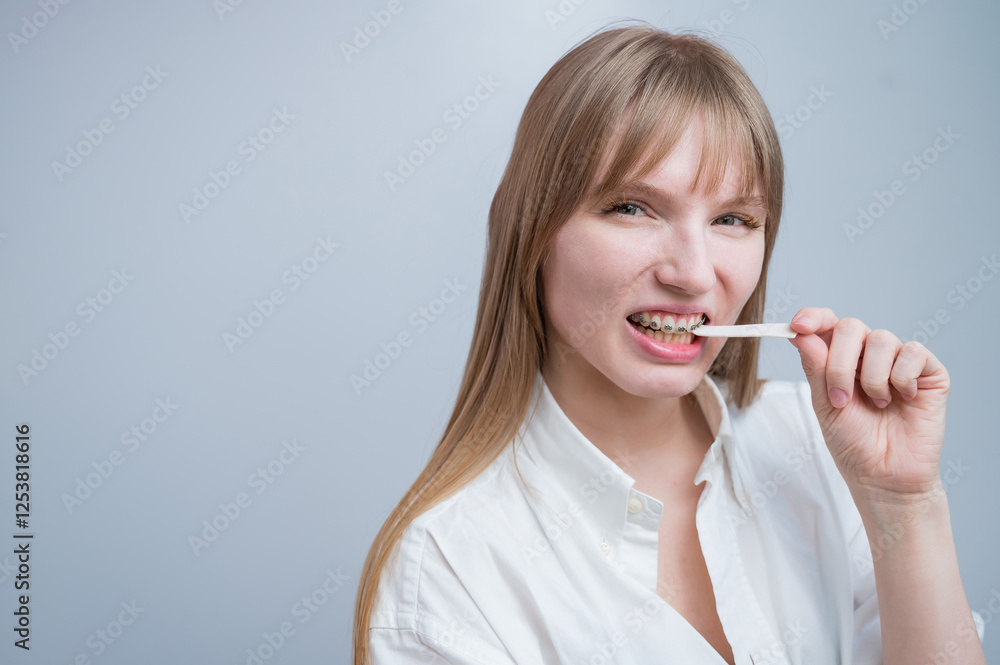 Young woman with metal braces on her teeth is chewing gum. The girl is eating gummy candy Young woman with metal braces on her teeth is chewing gum. The girl is eating gummy candy