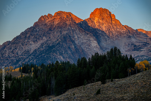 Rocky mountain top alpenglow with fall trees
