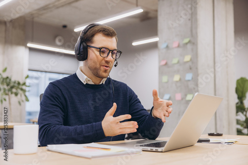 Photos Professional male worker communicating during video call, wearing headset, glass