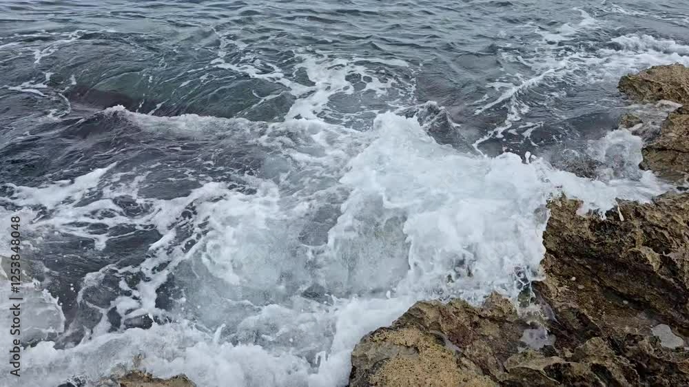 small sea waves crash against the rocks. small sea waves crash against the rocks.