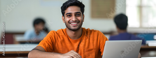 An Indian student sitting in the classroom and smiling while using their laptop
