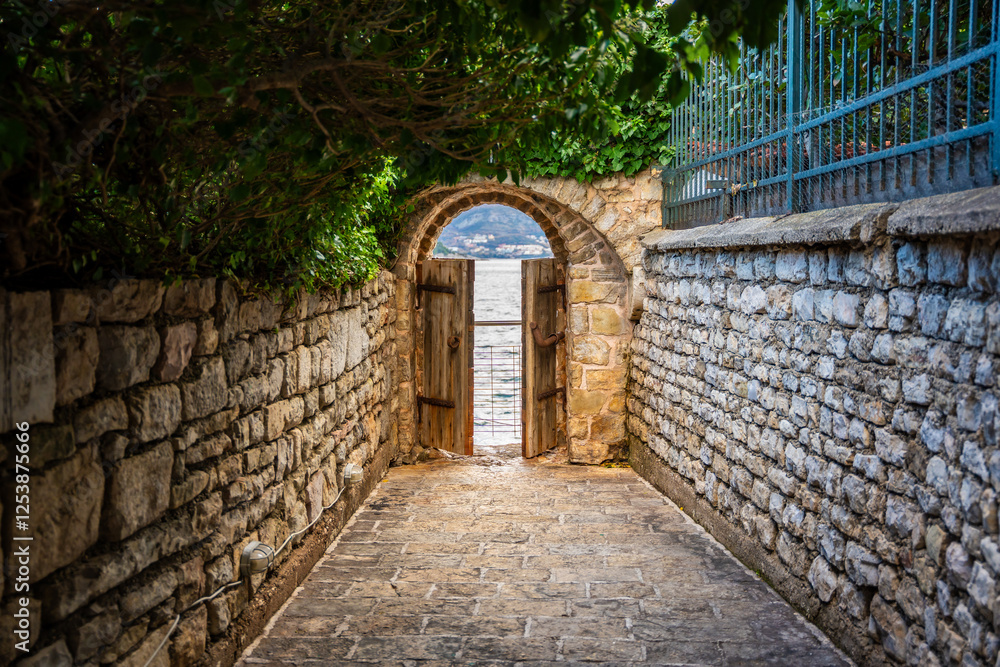 Old street in old town of Budva without people in winter time with small gate in the end to sea coast, Montenegro. Old street in old town of Budva without people in winter time with small gate in the end to sea coast, Montenegro.