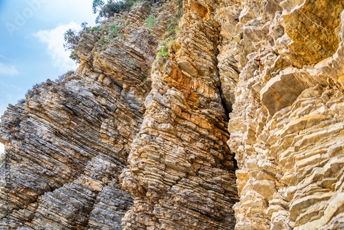 Layered rock texture in Budva, Montenegro. Sedimentary rocks with rugged surface of gray and brown. Natural formation of layers and cracks, geological structure. photo