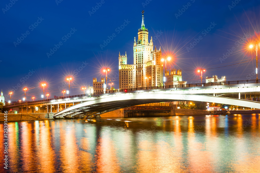 A high-rise building on Kotelnicheskaya embankment and Bolshoy Ustinsky bridge at night. Moscow