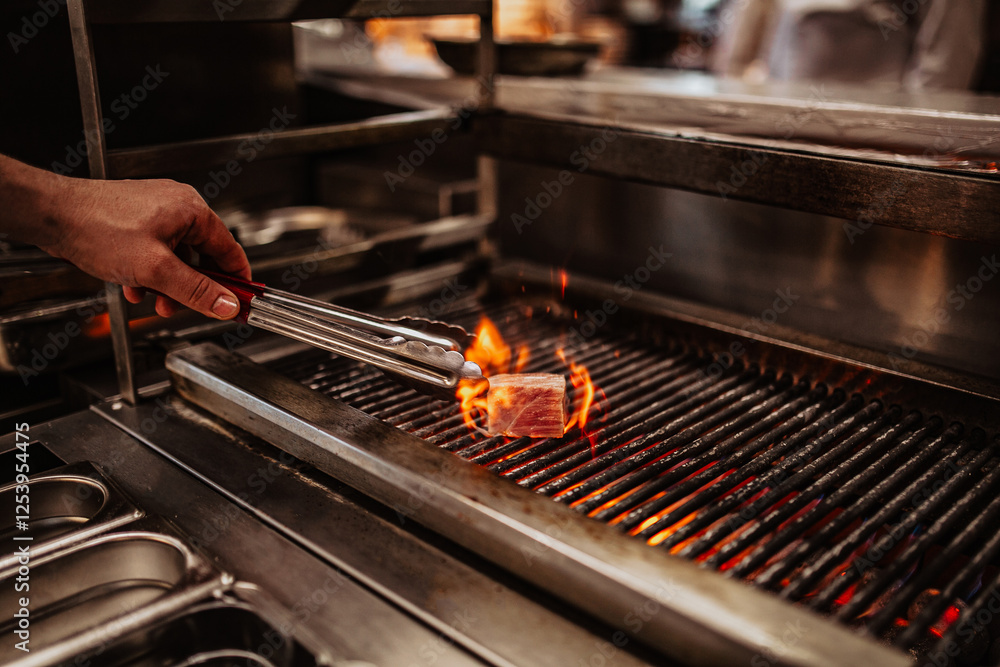 A close up shot of a delicious meat grilled in a restaurant kitchen with bright flames coming out of it A close up shot of a delicious meat grilled in a restaurant kitchen with bright flames coming out of it