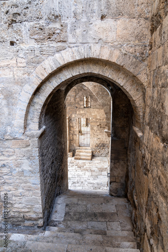 View from above of an ancient stone staircase under medieval stone arches photo