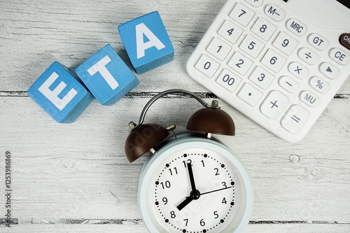 Valokuva ETA (Estimated Time Of Arrival) text with alarm clock and calculator on wooden b