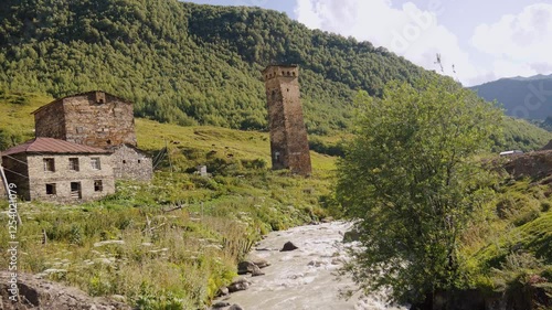 Wallpaper Mural Medieval stone Svan towers standing along flowing river stream reveal historical landscape of mountain valley with lush greenery and picturesque architectural heritage Torontodigital.ca