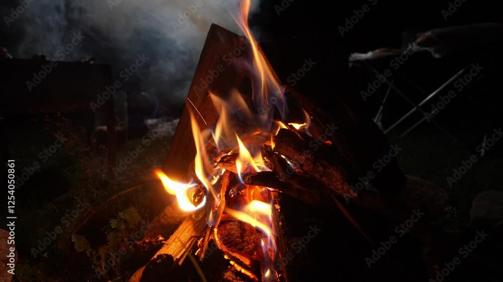 Close-up of campfire with logs and glowing embers, showcasing vibrant flames flickering against dark background, creating warm and cozy atmosphere Close-up of campfire with logs and glowing embers, showcasing vibrant flames flickering against dark background, creating warm and cozy atmosphere