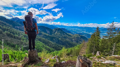 Man on alpine pasture with view of distant High Tauern mountain range from the Gailtal Alps. Scenery captures vastness of the Austrian landscape under a bright, partly cloudy sky. Remote Austria Alps photo