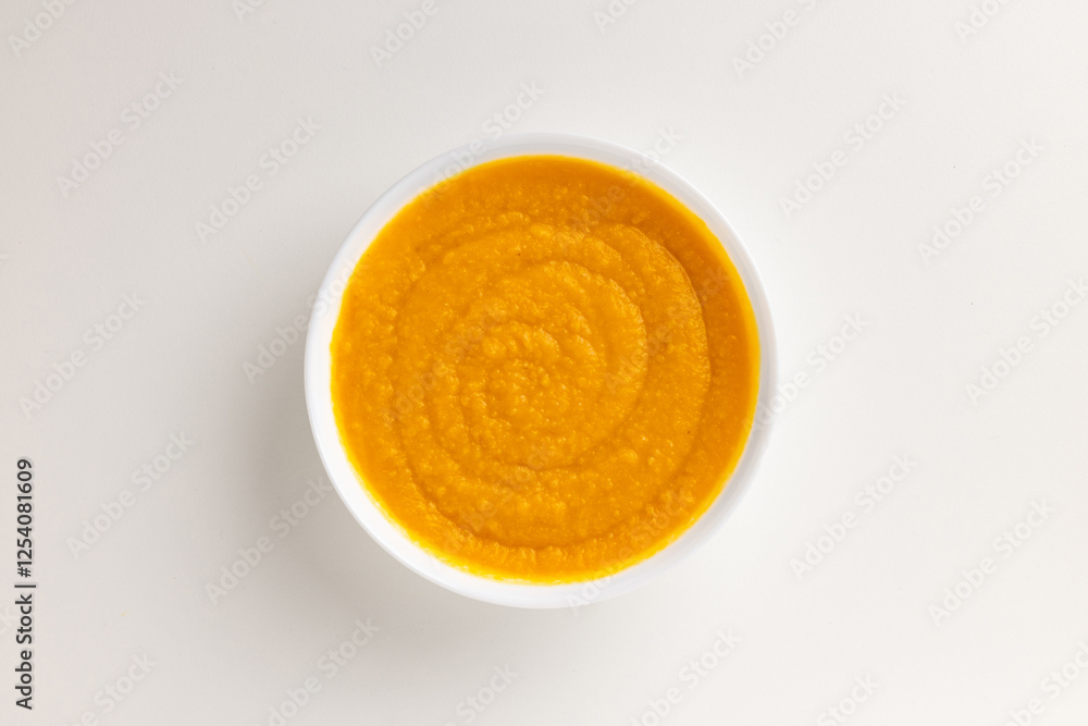 A top view of a round white bowl filled with creamy pumpkin and carrot soup, set against a white background. Simple, clean design, perfect for food styling, product mockups, or promotional use. A top view of a round white bowl filled with creamy pumpkin and carrot soup, set against a white background. Simple, clean design, perfect for food styling, product mockups, or promotional use.