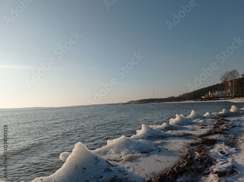 Serene Winter Seascape with Icy Shoreline and Calm Blue Waters, Capturing the Tranquility of a Frozen Beach at Sunset