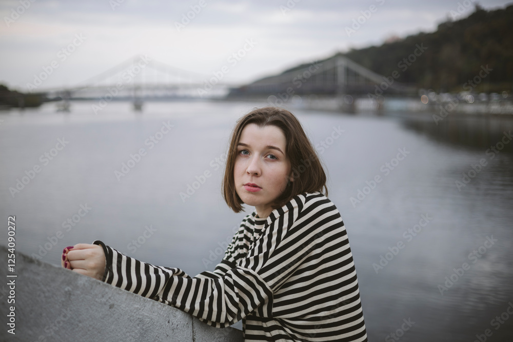 Pensive young woman near the river on the background of the city river. Pensive young woman near the river on the background of the city river.