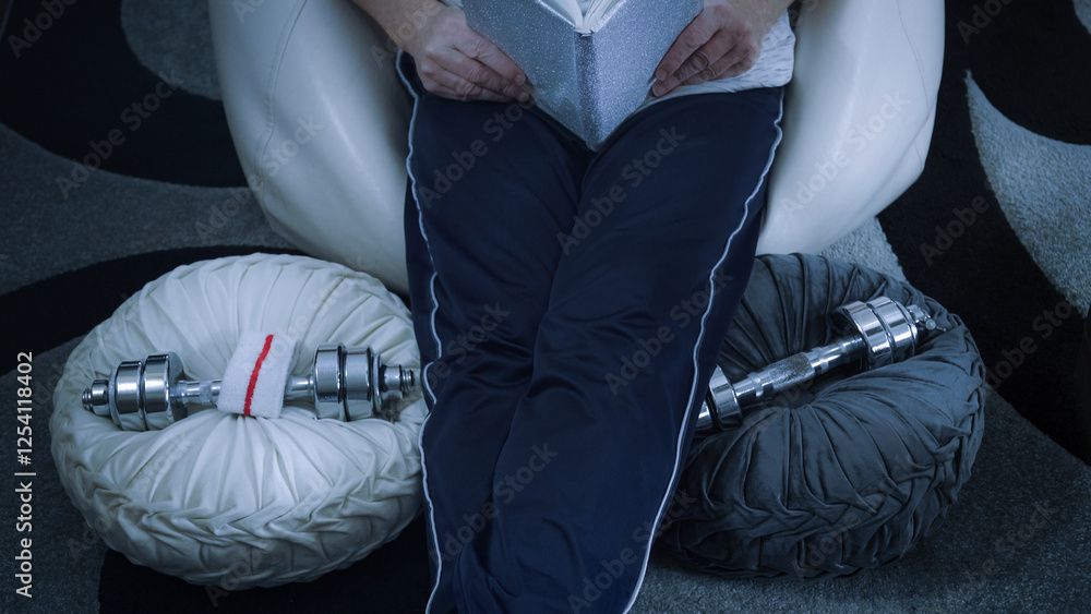 Athlete reading a book while resting after home workout session