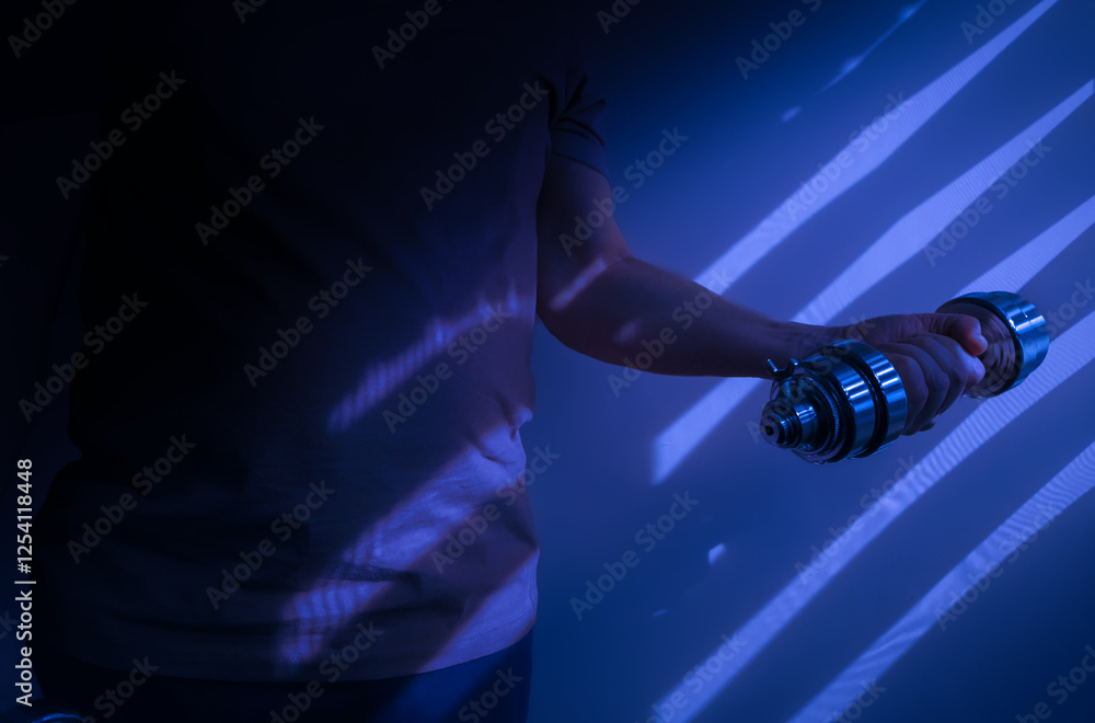Athlete lifting dumbbell showing muscle tension in dramatic lighting