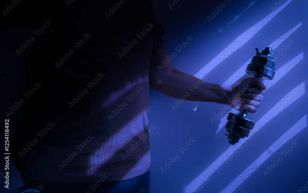 Athlete lifting dumbbell in dramatic blue light and shadows