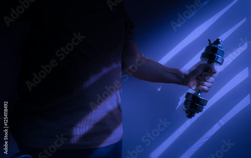 Obraz na płótnie Athlete lifting dumbbell in dramatic blue light and shadows w salonie