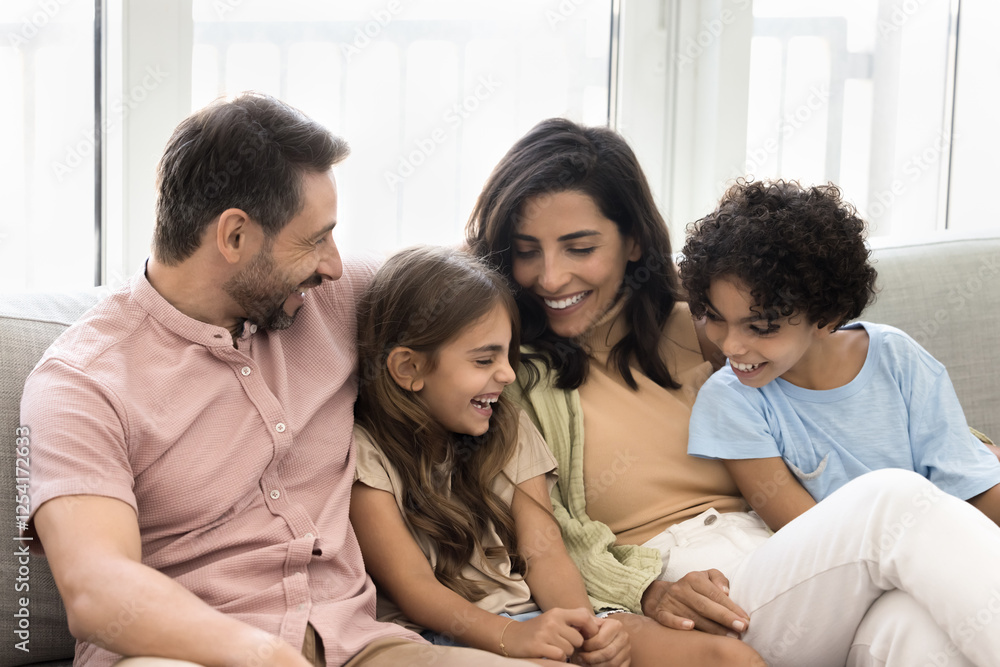 Joyful moments shared by family. Multiethnic parents and cute children sit closely on couch and laughing together, enjoying funny story or playful interaction, exude sense of love, warmth, and bonding Joyful moments shared by family. Multiethnic parents and cute children sit closely on couch and laughing together, enjoying funny story or playful interaction, exude sense of love, warmth, and bonding