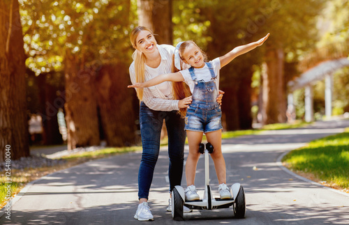 Joyful Mother And Daughter Riding Segway Having Fun In Park Outside. Family Weekend Adventure photo