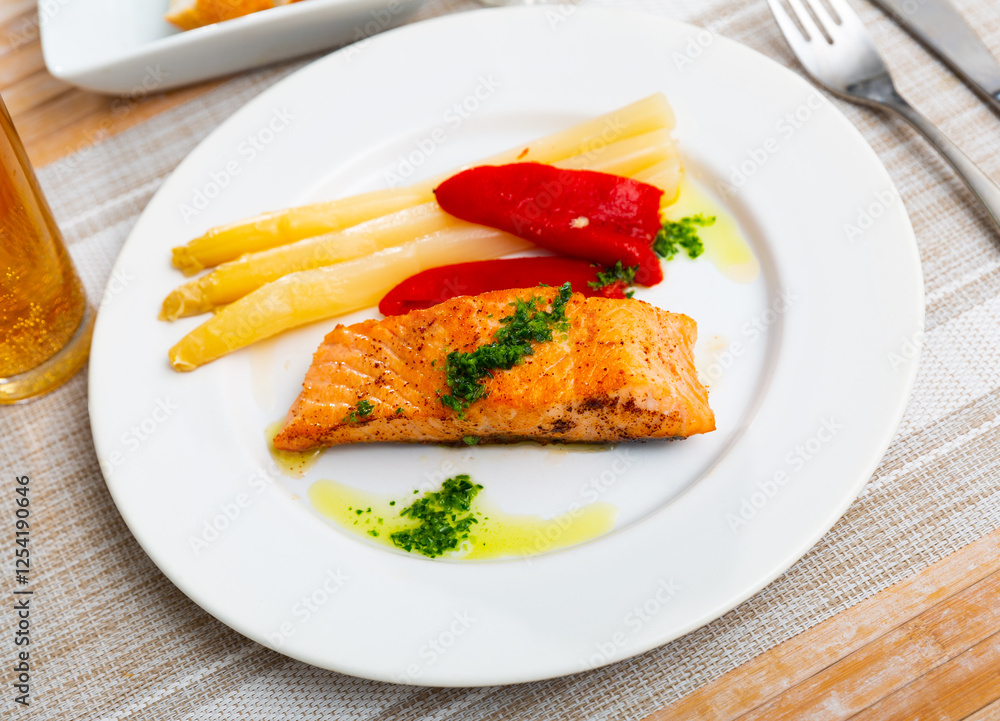 Grilled salmon with asparagus, pepper and herbs on a white dish in a restaurant Grilled salmon with asparagus, pepper and herbs on a white dish in a restaurant