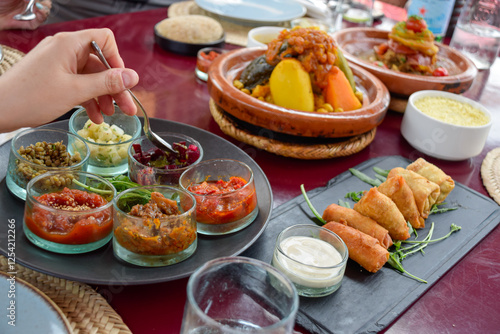 Hand serving food in table with Moroccan cuisine dishes as cous cous and tajin
