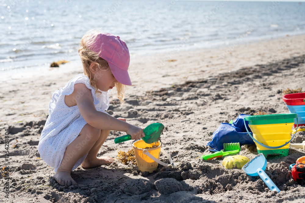 Little girl playing with beach toys in the sand. Summer ocean tropical vacation concept. Kids summer activities. Little girl playing with beach toys in the sand. Summer ocean tropical vacation concept. Kids summer activities.
