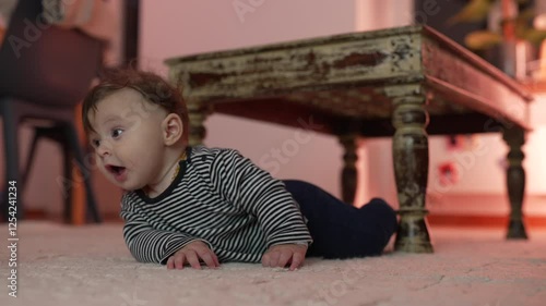 Baby resting head on floor, appearing contemplative and tired, relaxed position near rustic wooden table, moment of rest during tummy time, early development and self-soothing photo