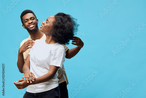 Happy couple embracing with joy against a bright blue background, showcasing love, connection, and vibrant emotions in casual clothing photo