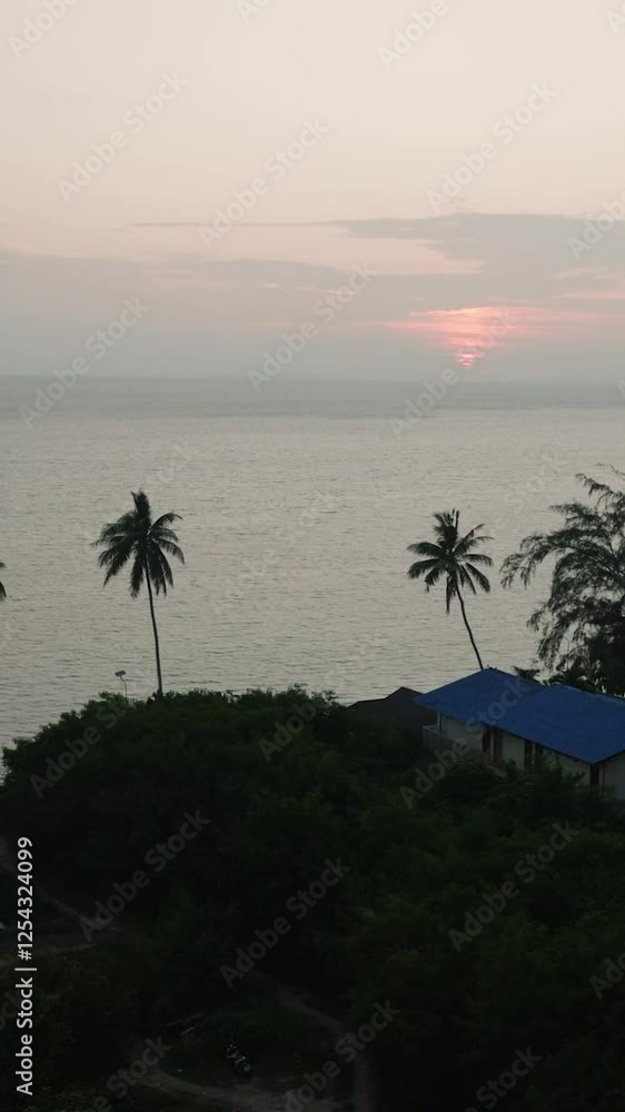 Sunset with pink sky reflecting on the calm sea, surrounded by palm trees and local houses. Ko Pha Ngan, Thailand. Sunset with pink sky reflecting on the calm sea, surrounded by palm trees and local houses. Ko Pha Ngan, Thailand.
