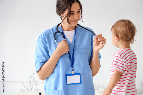 Happy female pediatrician with stethoscope and cute little baby in clinic