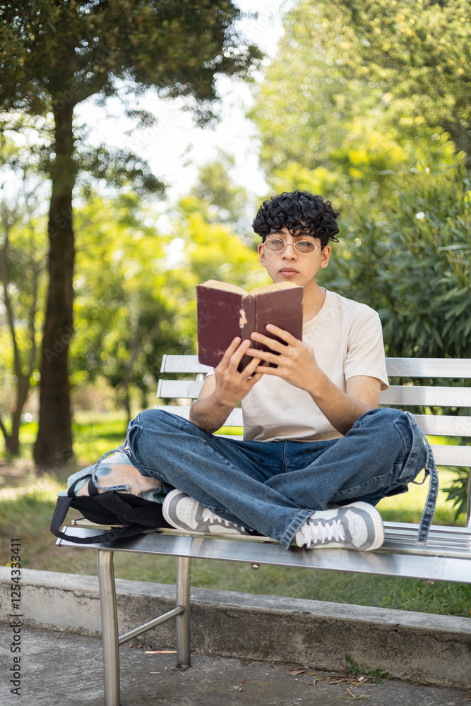 A young person reading a book while sitting cross-legged on a bench, relaxed and enjoying a peaceful moment, perfect for themes like reading, relaxation, and outdoor leisure. A young person reading a book while sitting cross-legged on a bench, relaxed and enjoying a peaceful moment, perfect for themes like reading, relaxation, and outdoor leisure.