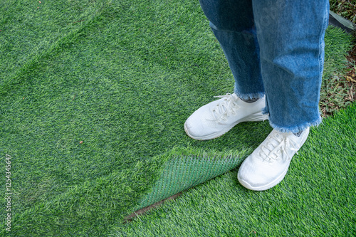 Cropped shot view of someone standing on incomplete green artificial turf. Artificial grass are made by polyethylene or nylon, convenient and it does not require much maintenance. photo